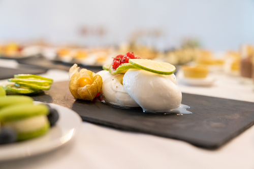 Burrata auf Schieferplatte mit Limette, Physalis und roten Beeren.