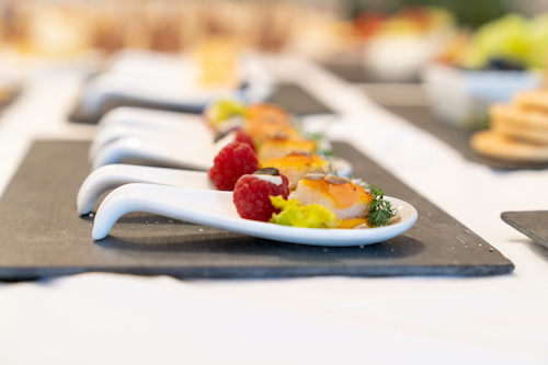 Gourmet-Häppchen auf Servierlöffeln mit Himbeeren und Kräutern.