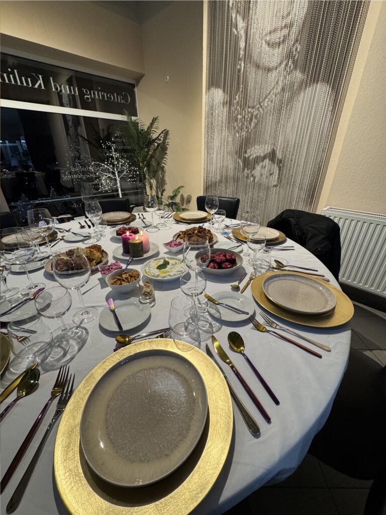 Festlich gedeckter Tisch mit goldenen Platztellern, Kerzen und Beilagen.