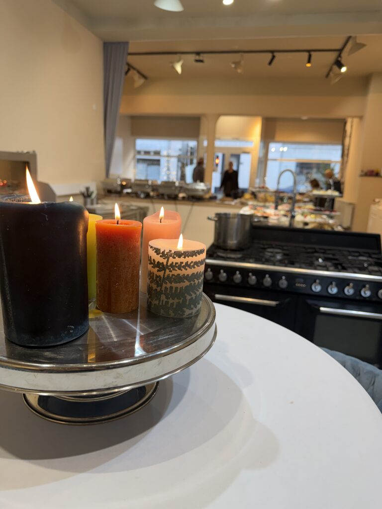 Kerzen auf Etagere vor moderner Cateringküche mit Buffetaufbau.